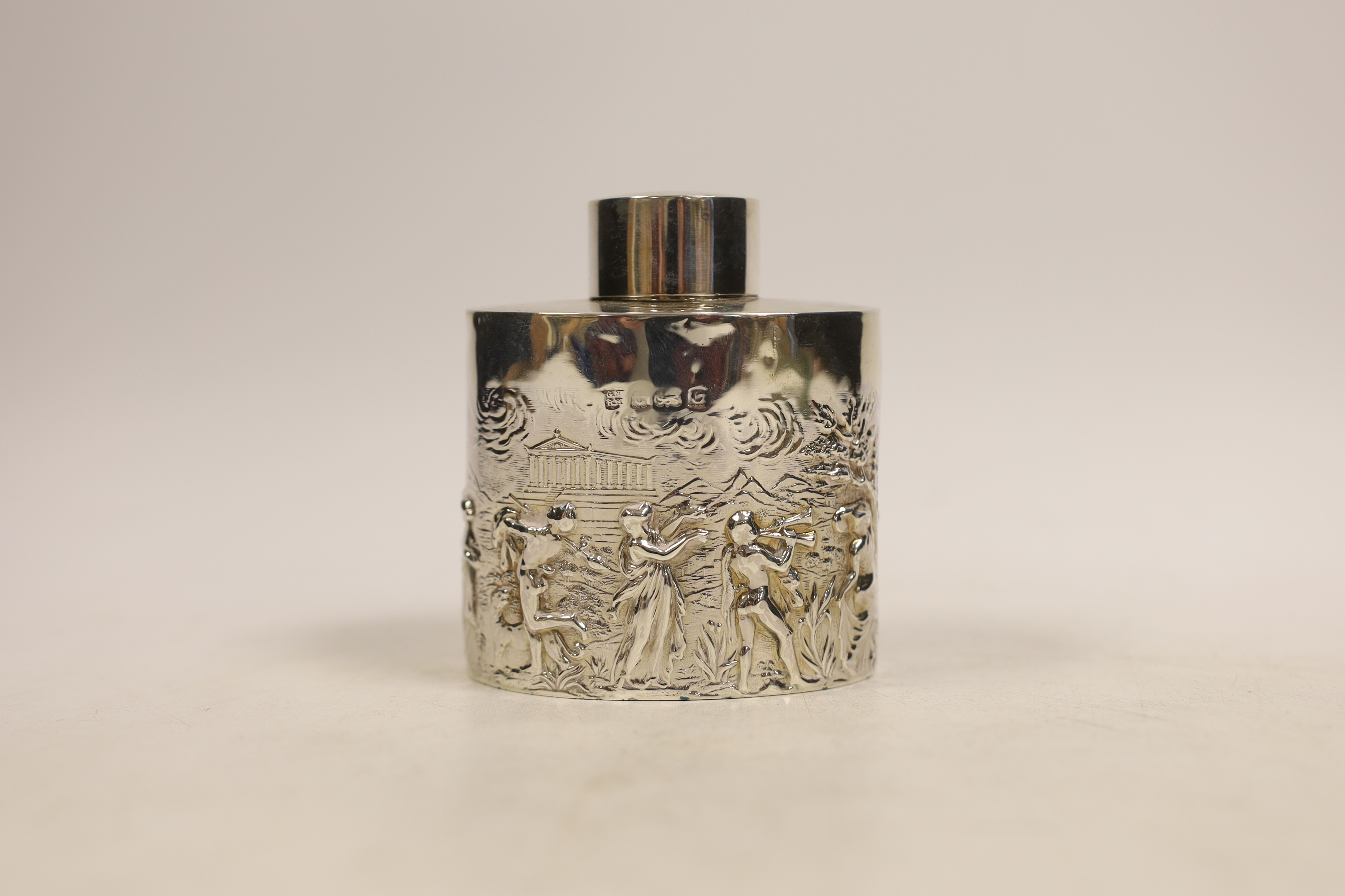 An Edwardian oval silver tea caddy embossed with all round Classical Greek imagery of figures, Parthenon and buildings, Nathan & Hayes, Birmingham, 1902, 90mm.